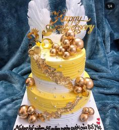 a three tiered cake decorated with gold and white decorations