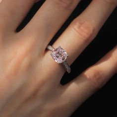 a woman's hand with a pink diamond ring on it