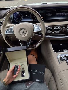 a woman holding a cell phone in her hand while sitting in the driver's seat of a car