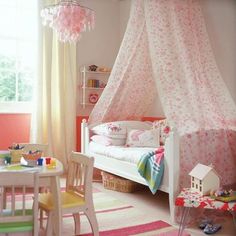 a child's bedroom with pink and white decor, including a canopy bed in the corner