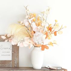 a white vase filled with flowers on top of a wooden table