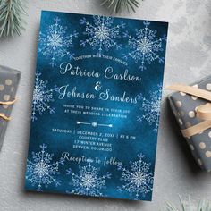 a blue and white wedding card with snowflakes on it, next to presents