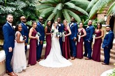 a group of people standing next to each other in front of trees and plants at a wedding