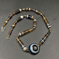 A beautiful Luk Mik Bead with rare shape and natural Pattern with natural Line in the center of Necklace along with 12 century khmer Angkor Empire Banded Agate Beads Luk mik means in Tibet (Goat's eye) or Ta Mik (horse eye) The beads got very shinny and smooth surface because of long passage of time using in necklaces and in prayers mala The agate beads were used in ancient times by rich Noble people of that time some orange color carnelian beads are used in necklace as spacers we provide fast a Beaded Agate For Jewelry Making, Agate Beaded Necklaces With Round Beads, Colorful Round Agate Beads, Large Agate Beads, Polished Agate Beaded Necklaces, Agate Necklace With Large Round Beads, Khmer Angkor, Noble People, Eye Band