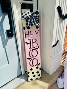 a wooden sign that says hey booo on it next to a door with a black and white polka dot bow