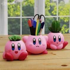 two pink ceramic planters with pens and pencils in them on a wooden table