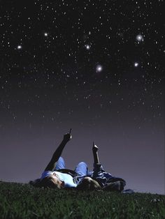 two people laying in the grass under a night sky with stars and planets above them