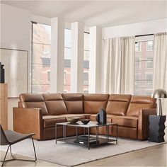 a living room filled with lots of furniture and large windows in the back drop down