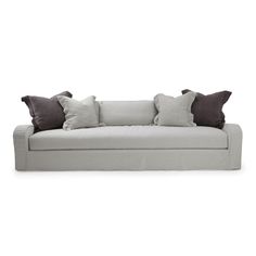 a white couch with some pillows on it's back and one pillow in the middle