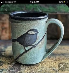 a coffee cup with a bird painted on the side sitting on top of a table