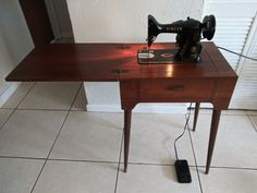 an old sewing machine sitting on top of a wooden table next to a phone charger