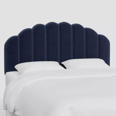 an upholstered headboard with white sheets and pillows