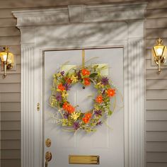 a wreath on the front door of a house decorated with flowers and leaves is shown