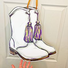 a hand is holding up a paper cutout of a boot with tassels