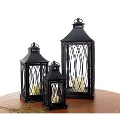 two black lanterns sitting on top of a wooden table next to each other with candles in them