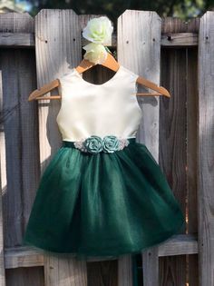 a green and white dress hanging on a wooden fence with a flower in the center