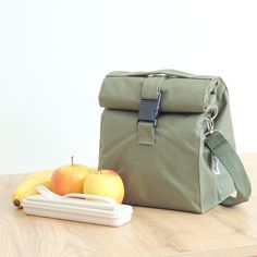 a lunch bag sitting on top of a wooden table next to an apple and knife