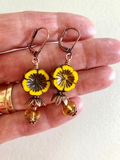 "Darling sunflower yellow Czech glass flower earrings with translucent amber crystal accents on copper ear wires. Sunflower yellow 15mm two-sided Czech glass flowers with tan and brown Picasso finish. Sparkling amber Picasso crystal rondelles dangle below sweet copper leaf bead caps. So delicate and summery with lots of movement! Flowers hang from antique copper lever backs. Total drop is 2\". Perfect pop of summery yellow!" Nickel Free Yellow Czech Glass Earrings, Nickel-free Yellow Czech Glass Earrings, Yellow Bohemian Nickel-free Flower Earrings, Yellow Flower Drop Earrings With Ear Wire, Adjustable Copper Flower Earrings, Gold Flower-shaped Czech Glass Earrings, Gold Flower-shaped Copper Earrings, Adjustable Nickel-free Yellow Flower Earrings, Gold Flower-shaped Earrings With Czech Glass