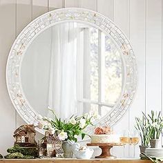 a table topped with a mirror and vases filled with flowers