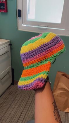 a woman's arm with a multicolored crocheted hat on it