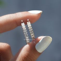 a woman's hand holding two diamond earrings