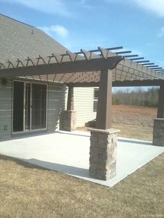 a patio with a pergolated roof and stone pillars