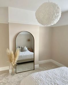 a bedroom with a bed, mirror and vase on the floor in front of it