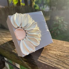 a white box sitting on top of a wooden table covered in frosting and pink icing