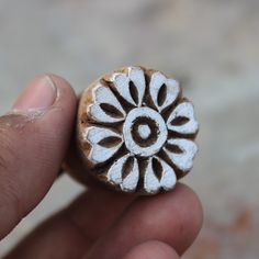 a hand holding a small wooden object with the letter o in it's center