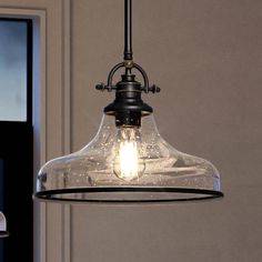 a clear glass light fixture hanging from a ceiling in a room with a door and window behind it