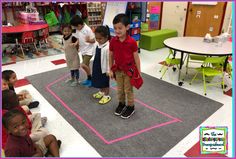 several children are sitting on the floor in a classroom and one child is standing up