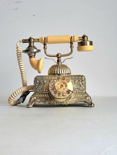 an old fashioned phone is sitting on a white surface with a cord attached to it