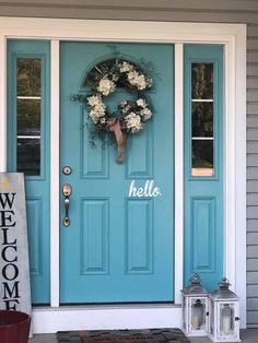 a blue front door with a wreath and welcome sign