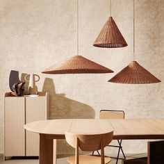 three wooden lamps hanging from the ceiling above a table