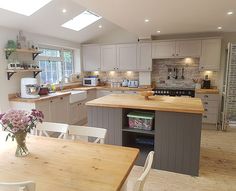 a kitchen with wooden floors and white cabinets is seen in this image from the dining room table