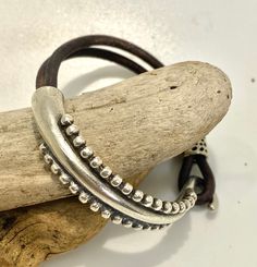 This is called a half cuff bracelet; it is half doubled soft brown leather cord and half silver alloy metal with a hook closure. The metal is bright silver zamak which is hypoallergenic, lead free and tarnish resistant.  To me it resembles the tentacles of an octopus arm, but others have said it looks more like the frond of a fern - I will leave that up to you to decide but either way it is quite pretty!  It looks great on its own or stacked with other bracelet pieces such as beadwork or chains.  We have only one of these special pieces and it is sized to fit a 15 to 17 cm wrist (6 to 7 inch) - this is about a small to average women's size.  Check out our shop to see our other unusual jewelry pieces.  We offer free shipping over 35 dollars and we ship quickly too! Adjustable Brown Wrap Bracelet, Adjustable Silver Double Band Leather Bracelet, Adjustable Double Band Silver Leather Bracelet, Silver Adjustable Double Band Leather Bracelet, Silver Double Band Adjustable Leather Bracelet, Nickel Free Brown Wrap Bracelet As Gift, Nickel-free Brown Wrap Bracelet As Gift, Nickel Free Brown Wrap Bracelet For Gift, Nickel-free Brown Wrap Bracelet Gift