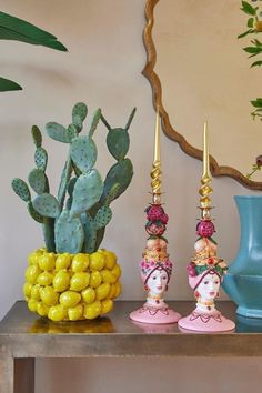 three colorful vases are sitting on a table with cacti and succulents