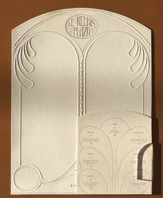 the inside of a white wedding card with an intricate design on it, and two matching envelopes