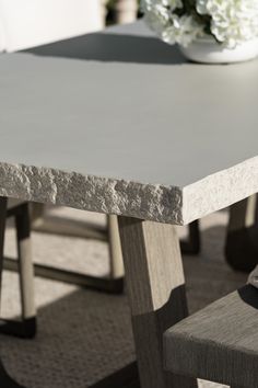 a table with two chairs and a vase on the table in front of it that has white flowers