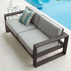 a couch sitting next to a swimming pool on top of a white tile covered floor