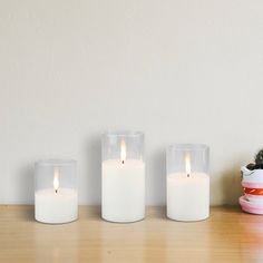 three white candles sitting on top of a wooden table