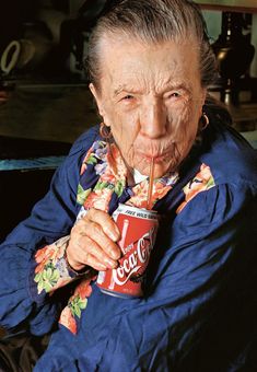 an old woman holding a can of coca cola