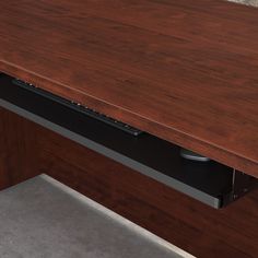 a close up of a wooden desk with a metal drawer on it's left side