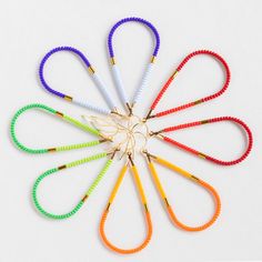 six different colored scissors are arranged in the shape of a flower on a white surface