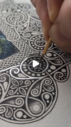 someone is using a pen to draw a design on paper with black and white ink