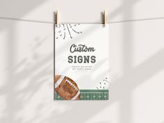 a sign hanging from a clothes line with a football on it that says custom signs