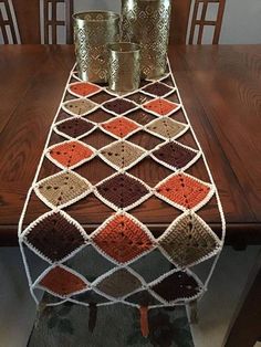 a crocheted table runner on top of a wooden table