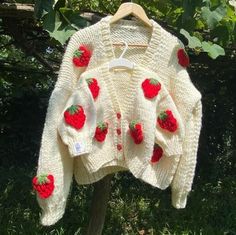 a white sweater with strawberries on it hanging from a tree