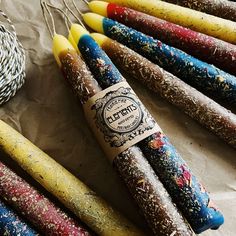 several different colored candles sitting next to each other on a piece of paper with twine baskets in the background