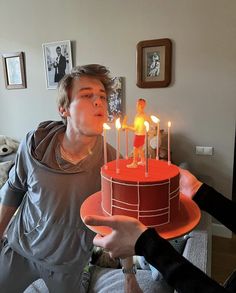 a man holding a cake with candles in it